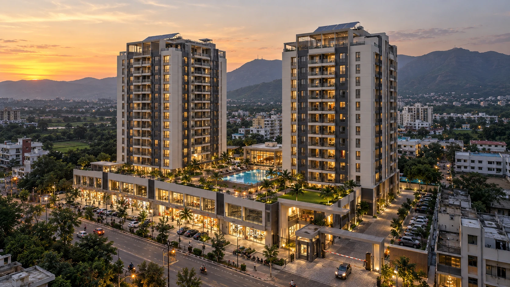 Illustrative aerial render at sunset of two residential towers with solar panels on their terraces, a podium of lit shops along the main road, a swimming pool and lawns on the podium deck, a gated entry and car parking, with green hills behind
