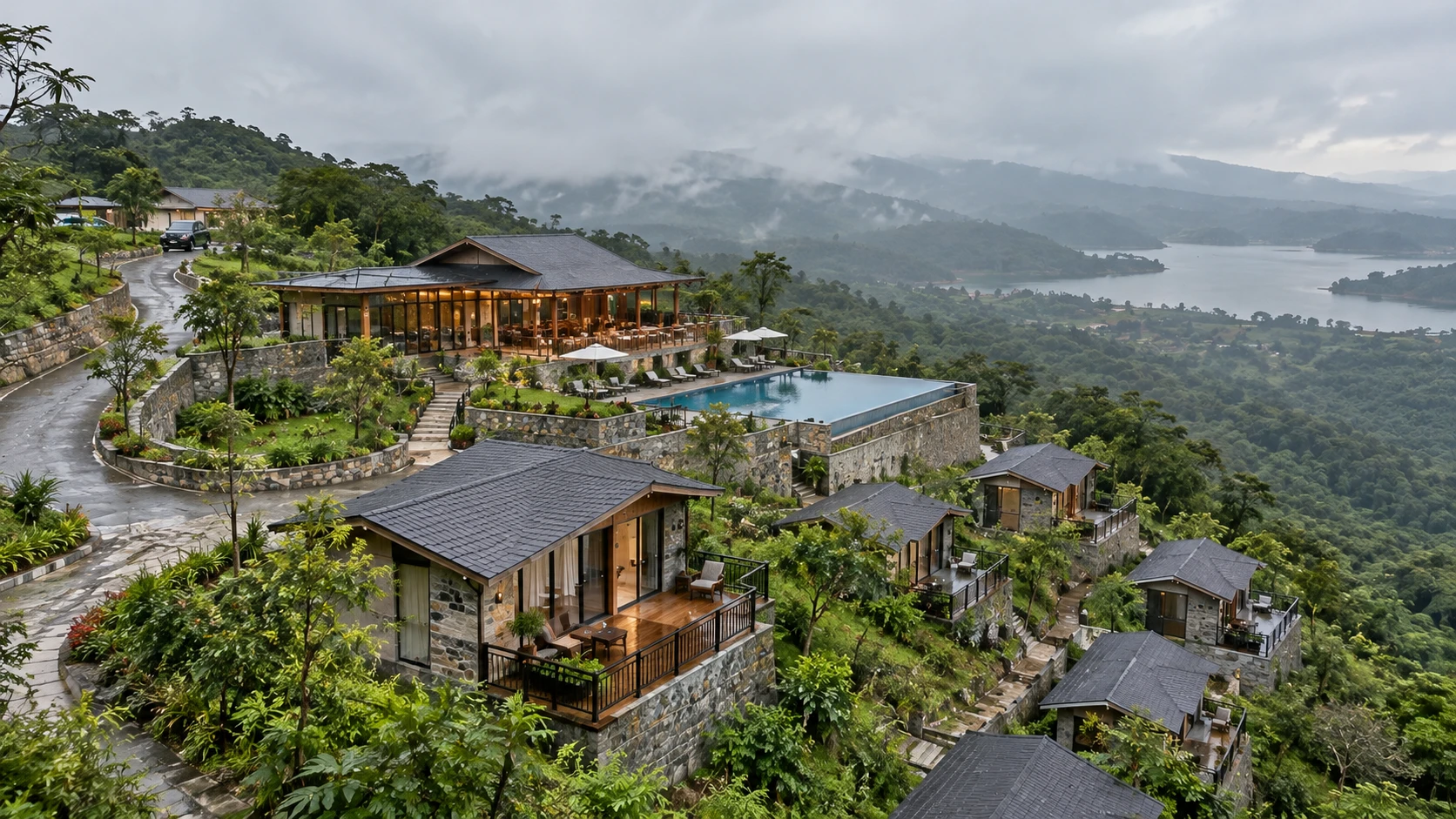 Illustrative render of a hillside resort in the monsoon, with stone cottages and decks stepping down a green slope, an infinity pool, a timber-roofed hall, a winding road with stone retaining walls and a reservoir among misty hills