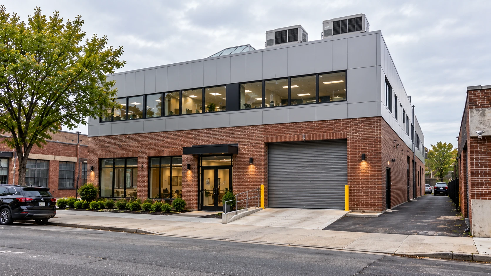 Illustrative image of a brick warehouse and office building in the Bronx with a new metal-panel upper floor, garage door and rooftop condensing units