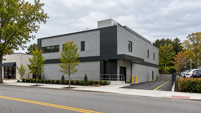 Illustrative image of a new two-storey storage building with metal siding and a loading dock on a corner lot in Great Neck