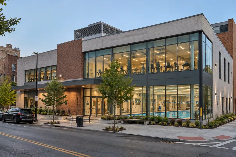 Illustrative image of a new outpatient rehabilitation centre with a glazed therapy pool hall and gym at dusk